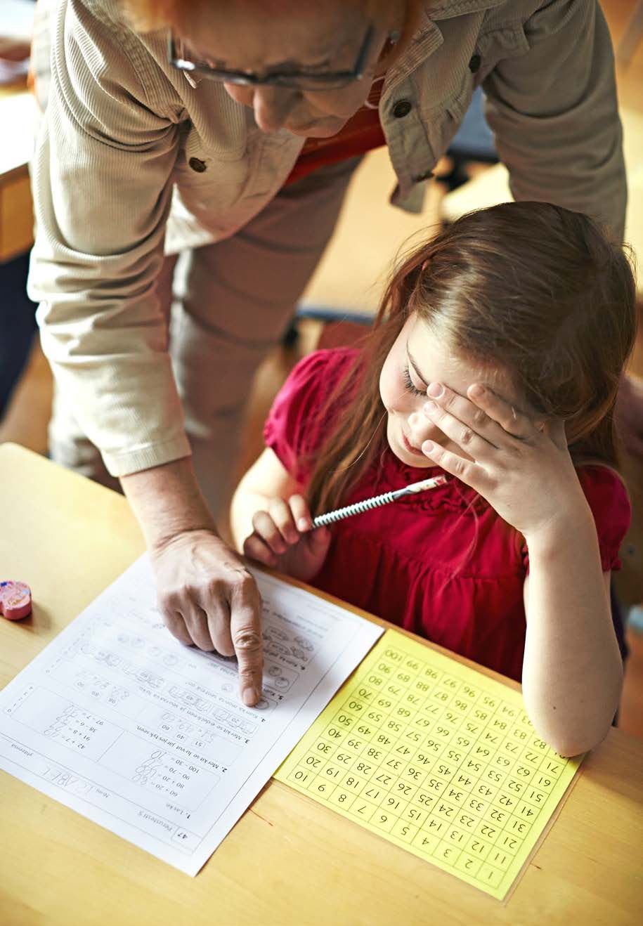 Kaisa neuvoo Isabelille täysien kymppien vähentämistä ja lisäämistä. Keltainen sataruudukko auttaa hahmottamaan kymmenjärjestelmää.