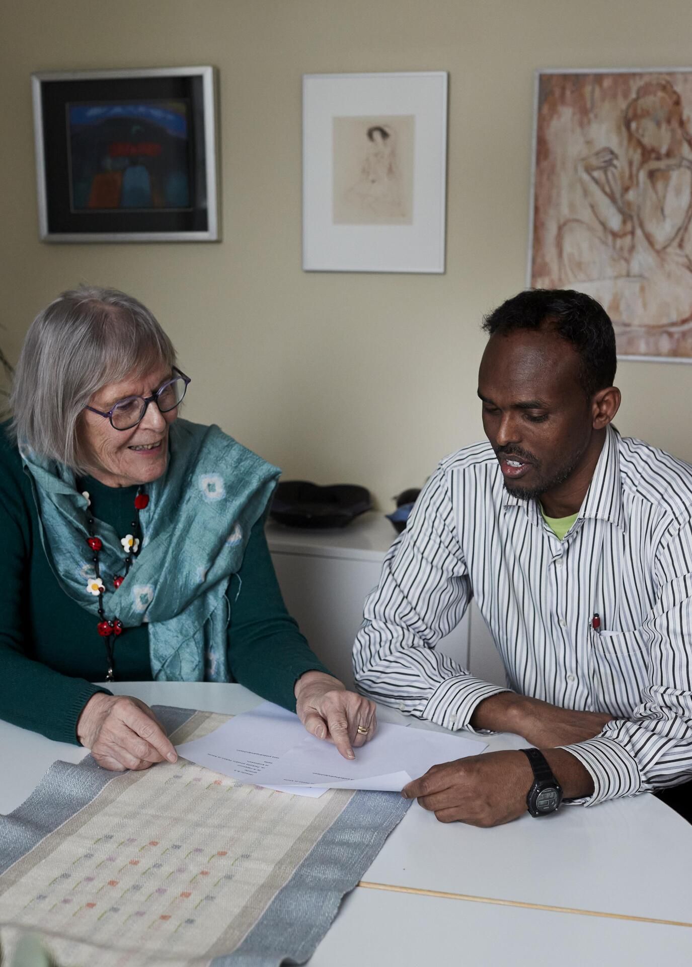 Marja Liisa Toivanen auttaa lähihoitaja Ahmed Muhammedia suomen kielen ja paperiasioiden kanssa.