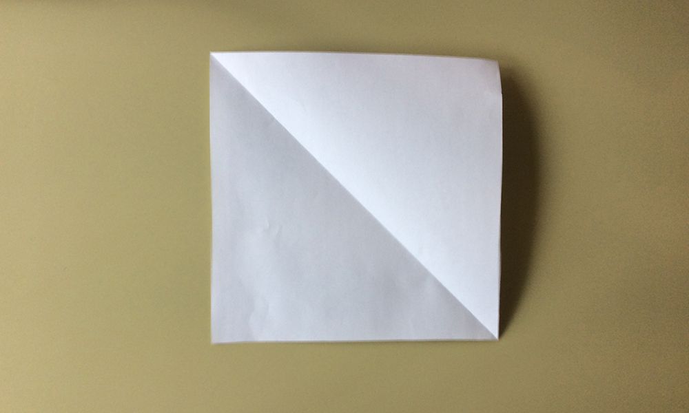 3. Taita neliö kolmioksi ja takaisin, niin että taitettuun kohtaan jää viiva.