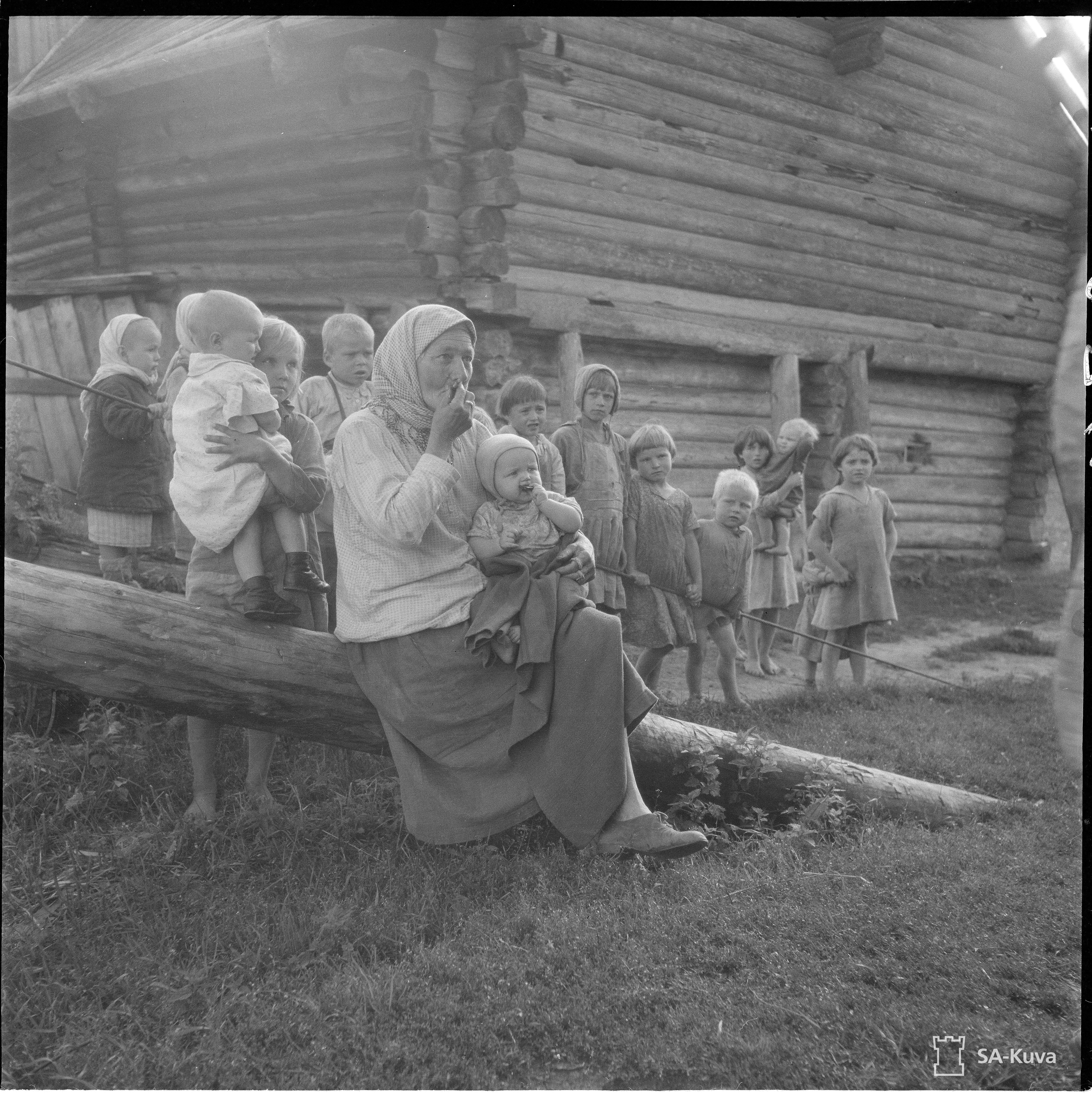 Vanha mummo kertoilee kokemuksiaan Uteliaat lapset ympäröivät. Metsoiniemi 1942.